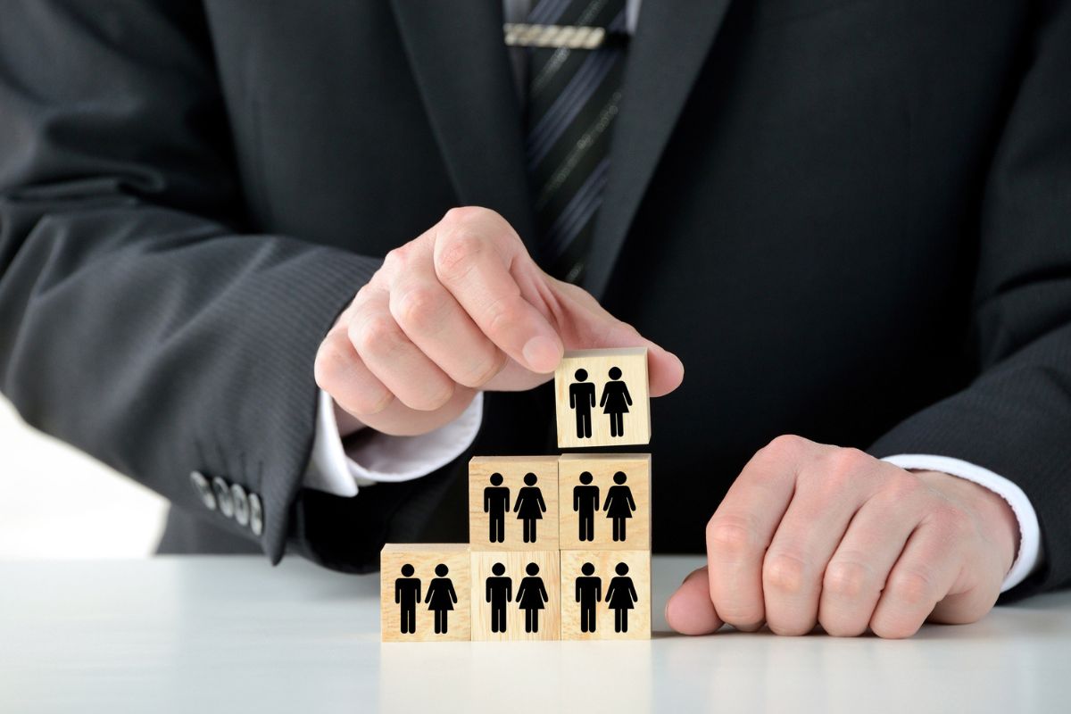 Business professional stacking wooden blocks with people icons representing audience growth and brand awareness.