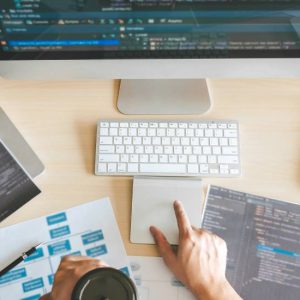 Website development and digital marketing solutions planning with coding screens, laptops, and workflow strategy on desk